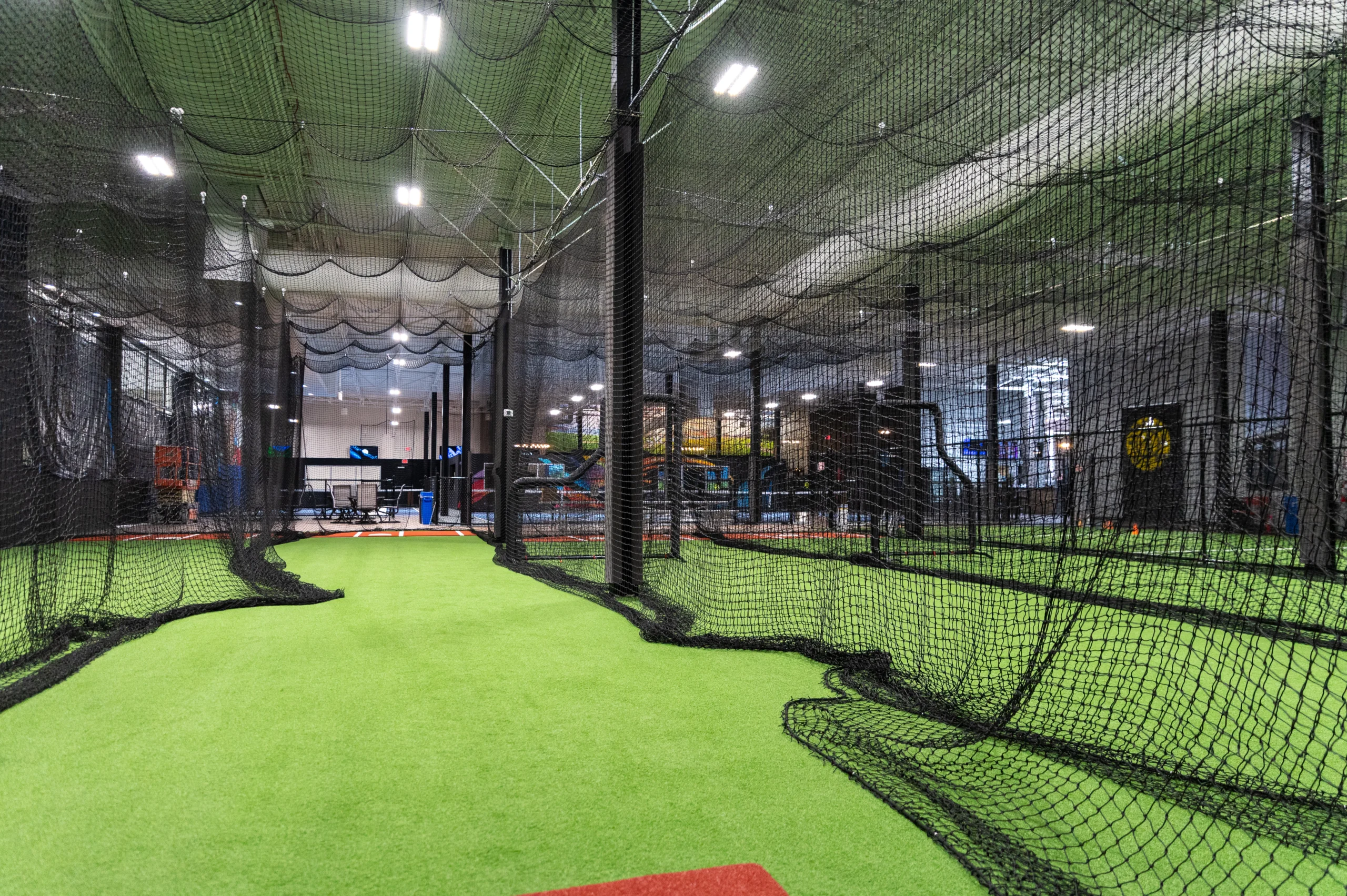 Batting cage tunnels under a canopy of netting across the turf
