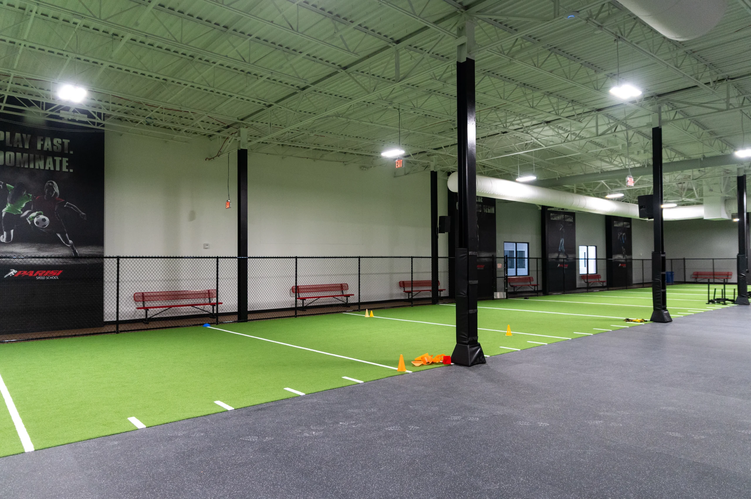Turf speed and agility lanes beside a Play Fast Dominate wall graphic