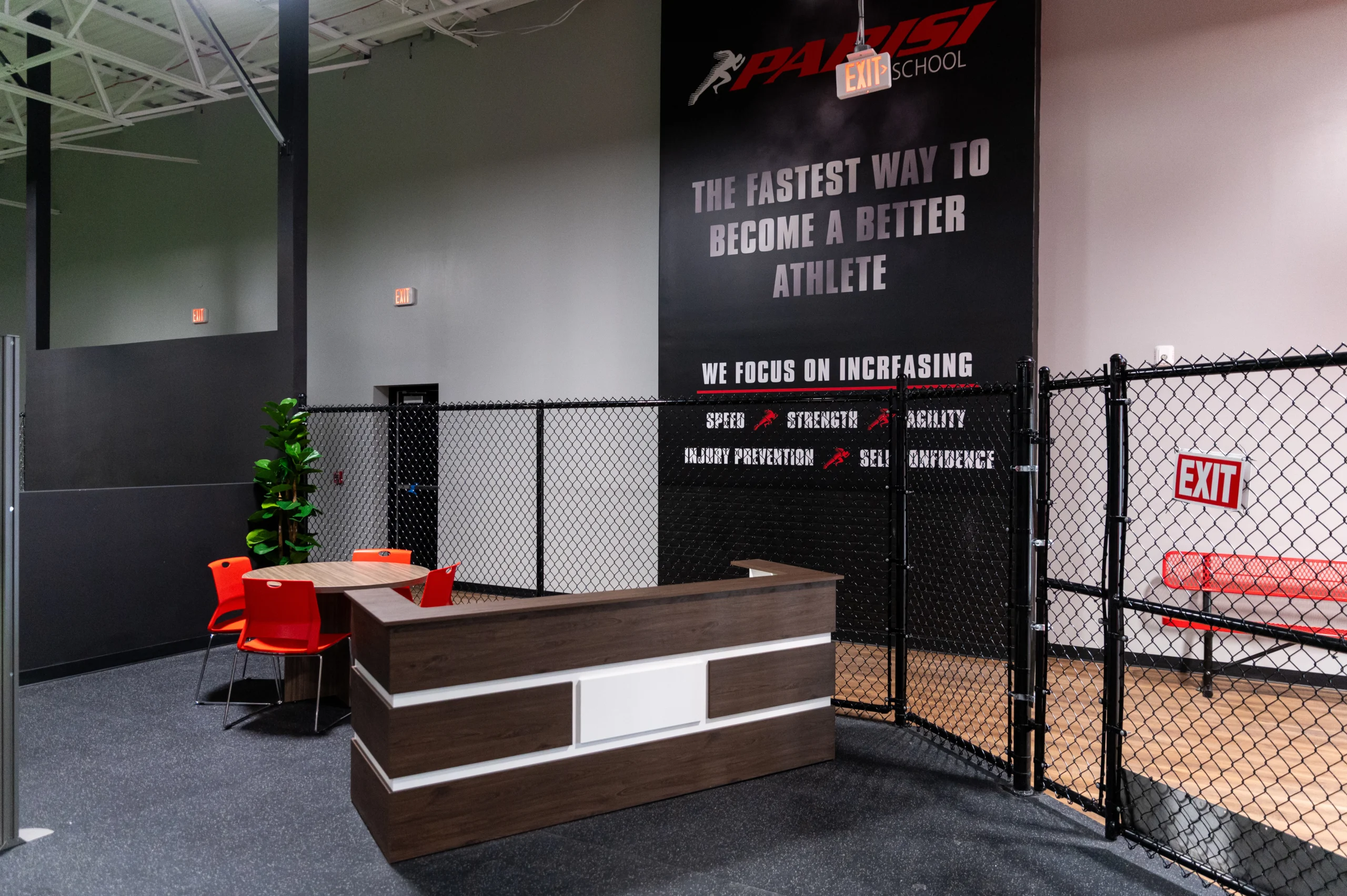 Front desk and family seating area beneath the Fastest Way to Become a Better Athlete wall
